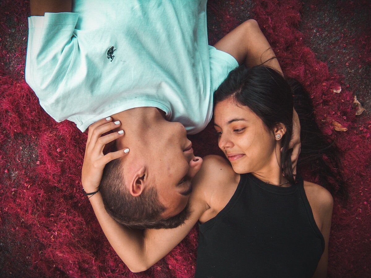 Couple Lying on Ground While Holding Their Hands