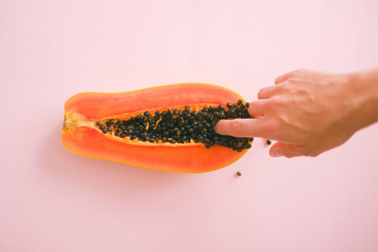 Crop faceless woman touching cut sweet papaya