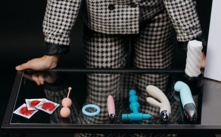A Woman Looking at a Variety of Sex Toys and Condoms on a Table